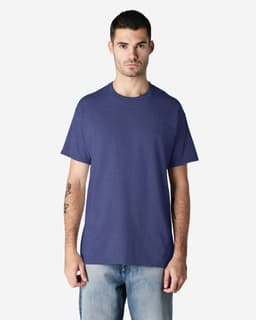 A man wearing a purple Gildan Ultra Cotton adult t-shirt and light blue jeans, standing against a plain background.
