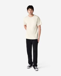 An adult t-shirt in cream colour displayed on a model wearing black pants and shoes. The shirt features a logo.
