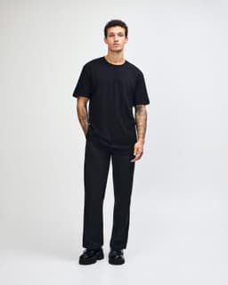 A black unisex fine jersey short sleeve t-shirt displayed on a model, featuring a simple design and relaxed fit.