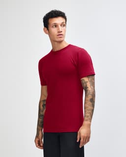 A maroon unisex short sleeve t-shirt displayed on a model from the side, featuring a plain design and a logo.