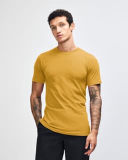 A unisex fine jersey short sleeve t-shirt in mustard yellow, displayed on a model with long hair.