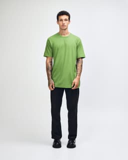 A unisex fine jersey short sleeve T-shirt in vibrant green, worn by a model in casual denim. It features a logo.