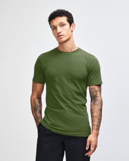 A unisex fine jersey short sleeve t-shirt in a rich green colour, displayed on a model with hands in pockets.