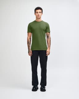 A green unisex short sleeve t-shirt worn by a model, paired with blue jeans and black shoes. Branding visible.