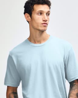 A unisex fine jersey short sleeve t-shirt in light blue, worn by a model with dark jeans and sneakers.