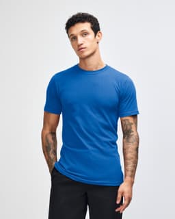 A blue short sleeve T-shirt on a model with tattoos, featuring a logo on the shirt.