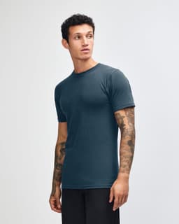 A unisex fine jersey short sleeve T-shirt in navy blue, featuring a logo on the side. Model standing sideways.