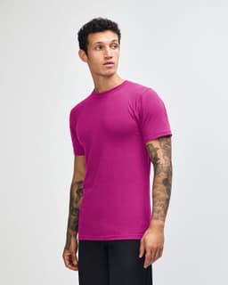 A unisex fine jersey short sleeve t-shirt in vibrant purple, worn by a model posing sideways. The shirt features a logo.