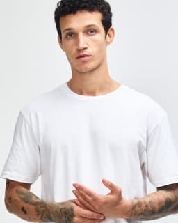 A white unisex short sleeve t-shirt displayed on a model paired with black leggings and white sneakers.