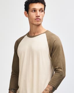 A unisex raglan T-shirt featuring a beige body and brown sleeves, with a model displaying the shirt.