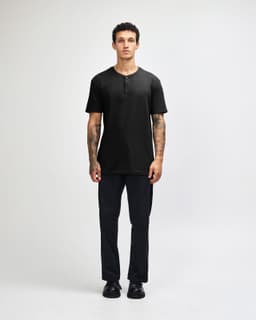 A unisex black henley T-shirt displayed on a model, featuring a buttoned neckline and short sleeves.