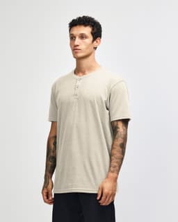 A unisex henley T-shirt in beige, featuring a round neckline and short sleeves, displayed on a model.