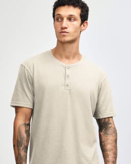 A unisex henley t-shirt in a light beige colour, featuring three buttons at the neckline and short sleeves.
