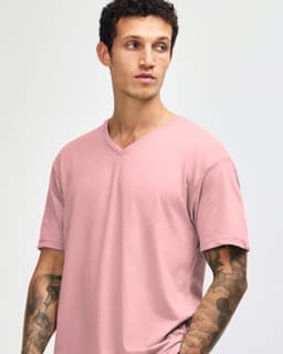 A pale pink unisex V-neck T-shirt on a model with tattoos, featuring a logo on the sleeve.