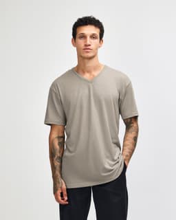 A unisex V-neck T-shirt in a muted beige colour with short sleeves and a relaxed fit. It features a logo on the garment.