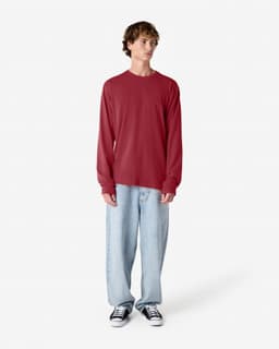 A long sleeve T-shirt in red, paired with light blue baggy jeans and black sneakers, featuring a logo.