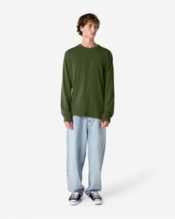 A long sleeve t-shirt in olive green, displayed on a model wearing loose-fitting light denim jeans and black sneakers.