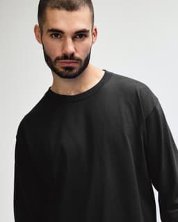 A model wearing a black long sleeve t-shirt made of ultra cotton, featuring a simple design and relaxed fit.