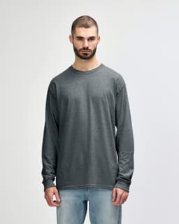 A long sleeve t-shirt in a dark grey colour, featuring a logo and worn by a man with short, styled hair.