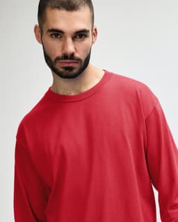 A red long sleeve t-shirt with a relaxed fit, featuring a logo on the front.