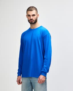 A long-sleeve T-shirt in bright blue, featuring a logo, worn by a model facing left.
