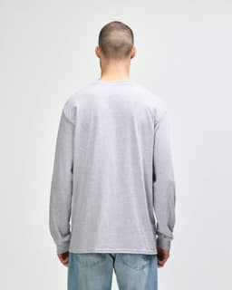 A woman wearing a grey Gildan Ultra Cotton adult long sleeve t-shirt, viewed from the back, paired with navy leggings.