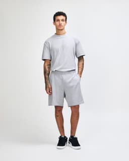 Grey unisex gym shorts with an elastic waistband and pockets, paired with black shoes and white socks.