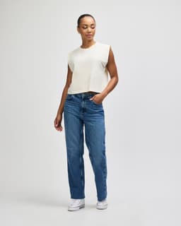 A cream-coloured muscle t-shirt worn with light blue cargo jeans, featuring a logo.