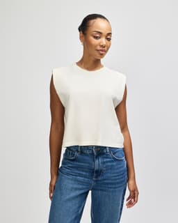 A cream-coloured muscle T-shirt with a relaxed fit and no sleeves, featuring a small logo.