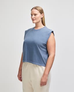 A sleeveless, cropped muscle t-shirt in deep blue, featuring a simple design and a logo.