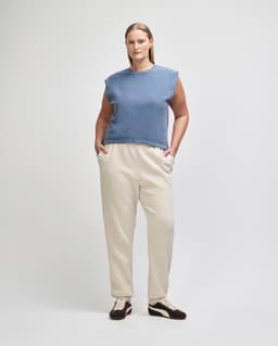 A navy blue women's muscle t-shirt is paired with light blue baggy jeans. The model stands in a neutral setting.