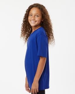 A blue youth performance T-shirt displayed on a smiling girl with curly hair, featuring a simple design and a logo.