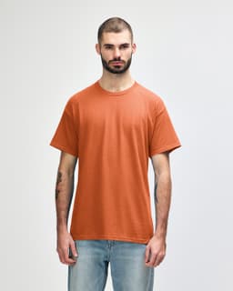 A man wearing a Gildan Heavy Cotton adult T-shirt in a vibrant orange colour, featuring a logo.