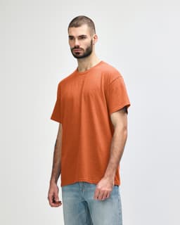 A plain orange adult t-shirt featuring a round neck and short sleeves, displayed on a model.