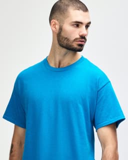 A blue Gildan Heavy Cotton adult t-shirt on a male model, featuring a plain design and a logo.
