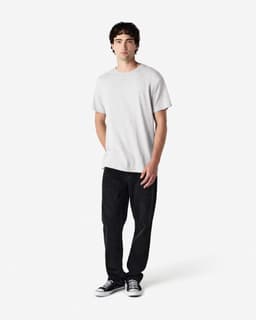 A light grey Gildan Heavy Cotton adult T-shirt worn with black pants and casual shoes, featuring a logo.