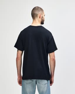 A black Gildan Heavy Cotton Adult T-Shirt displayed from the back, featuring short sleeves and a simple design.