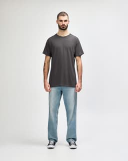 A grey Gildan Heavy Cotton Adult T-Shirt displayed on a male model, paired with black jeans and sneakers.