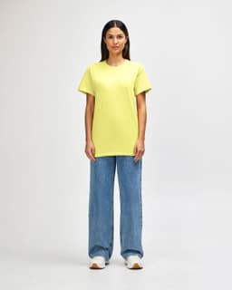 A man wearing a bright yellow Gildan Heavy Cotton adult T-shirt paired with blue jeans. The shirt has a logo.