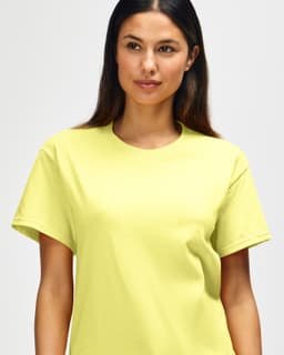 A close-up of a man wearing a bright yellow Gildan Heavy Cotton Adult T-Shirt. The shirt has a logo on it.