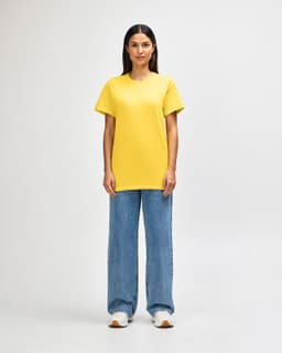 A yellow Gildan Heavy Cotton adult T-shirt worn by a male model, alongside black pants and sneakers.