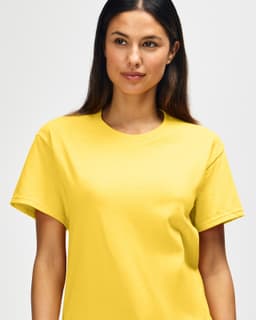 A yellow Gildan Heavy Cotton Adult T-Shirt displayed on a model, featuring a logo.
