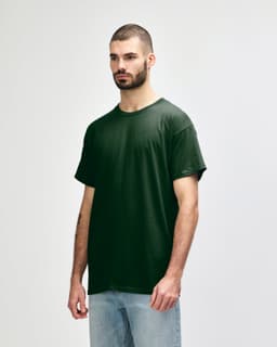 A green Gildan Heavy Cotton Adult T-Shirt displayed on a model, featuring a logo on the front.