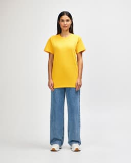 A man wearing a bright yellow Gildan Heavy Cotton T-shirt and black pants, standing with a neutral expression.
