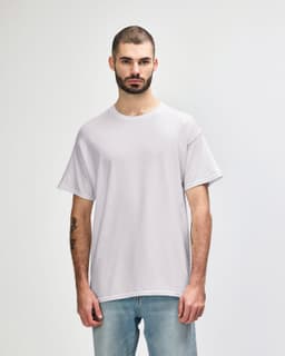 A light grey adult t-shirt displayed on a model, featuring a simple design and a branding logo.