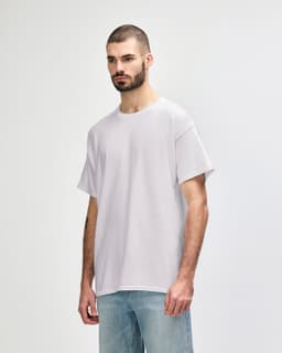 A grey Gildan Heavy Cotton Adult T-Shirt worn by a model, featuring a simple design and relaxed fit.