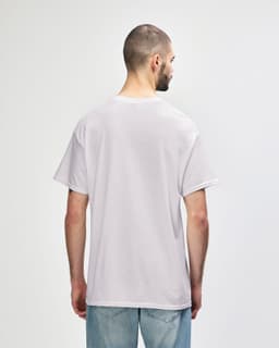 A man wearing a light grey Gildan Heavy Cotton Adult T-Shirt, viewed from the back. The shirt has a logo.