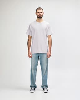 A man wearing a light grey Gildan Heavy Cotton Adult T-Shirt and blue jeans, standing against a plain background.