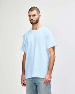 A light blue Gildan Heavy Cotton adult t-shirt is displayed on a model. It features short sleeves and a simple design.
