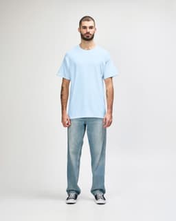 A light blue Gildan Heavy Cotton adult t-shirt displayed on a male model wearing black pants and sneakers.